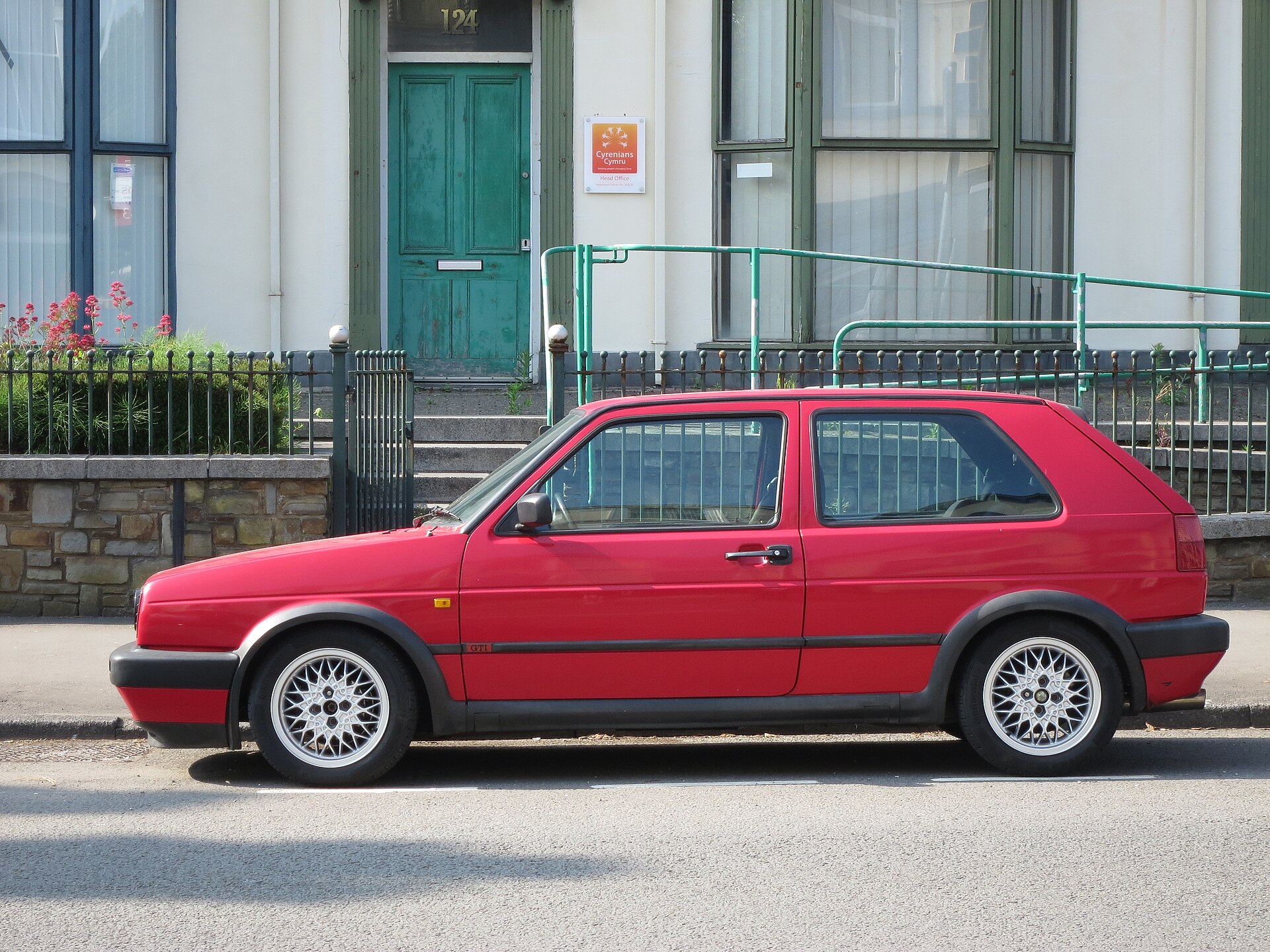 Roter VW Golf 2 GTI in der Seitenansicht mit BBS-Kreuzspeichen-Felgen und roter Zierleiste